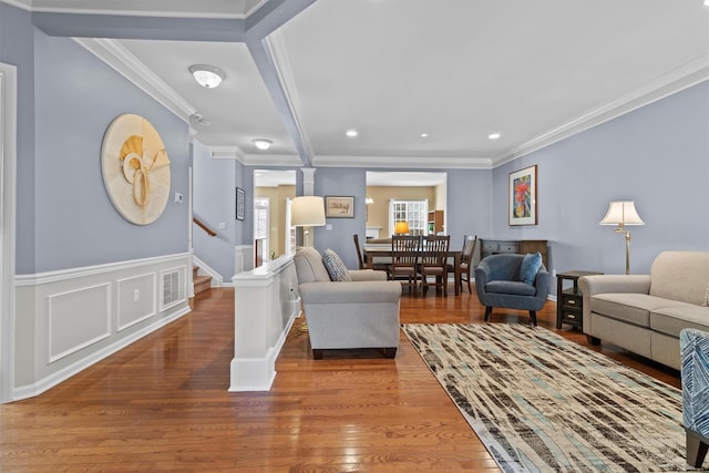 living room with wood-type flooring, ornamental molding, and ornate columns