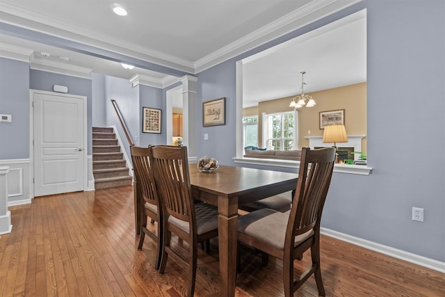 dining room featuring hardwood / wood-style flooring, ornate columns, crown molding, and a notable chandelier