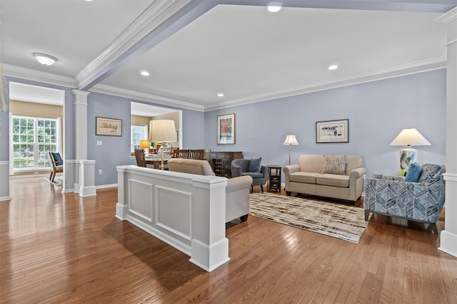 living room featuring hardwood / wood-style floors, crown molding, and ornate columns