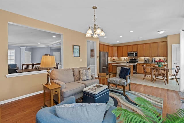 living room with a chandelier, crown molding, light hardwood / wood-style floors, and sink