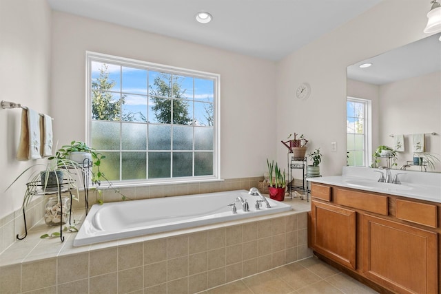 bathroom featuring tiled bath, vanity, and tile patterned flooring