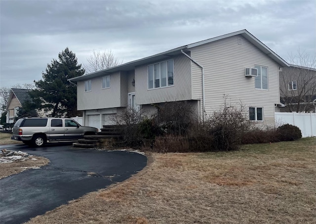 view of front of property featuring a garage, a wall unit AC, and a front yard