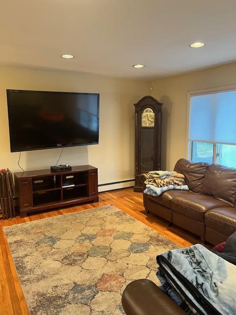 living room with baseboard heating and light hardwood / wood-style floors