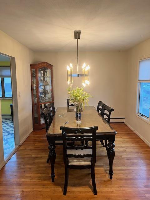 dining room with hardwood / wood-style floors, baseboard heating, and a notable chandelier