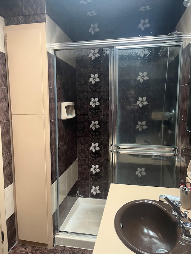 bathroom with a shower with shower door and sink