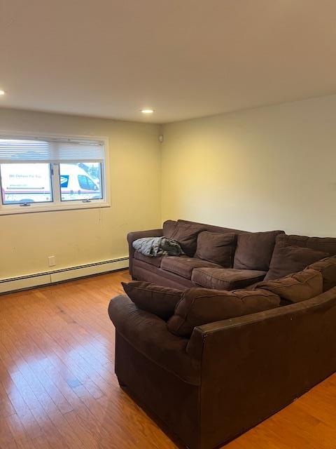 living room with a baseboard radiator and light hardwood / wood-style flooring