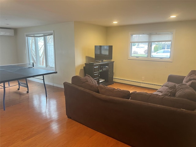 living room featuring an AC wall unit, a baseboard heating unit, and light hardwood / wood-style floors