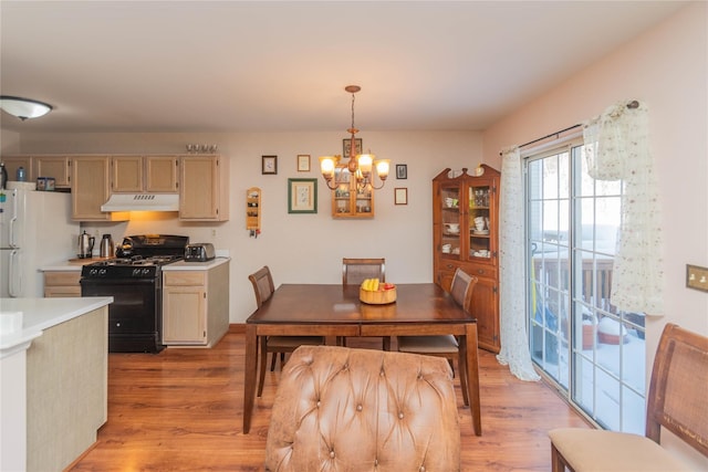 dining space with an inviting chandelier and light hardwood / wood-style flooring