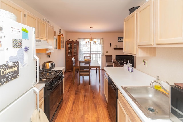 kitchen featuring extractor fan, decorative light fixtures, wood-type flooring, sink, and black appliances