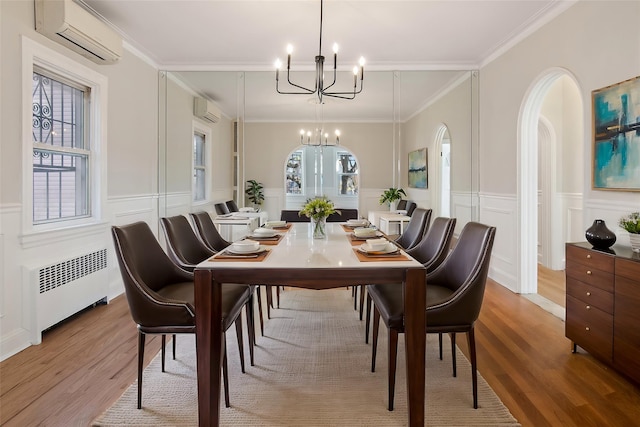 dining space with radiator, crown molding, a wall mounted AC, and light wood-type flooring