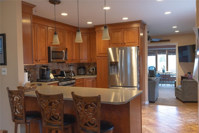 kitchen featuring a kitchen breakfast bar, stainless steel appliances, backsplash, and kitchen peninsula