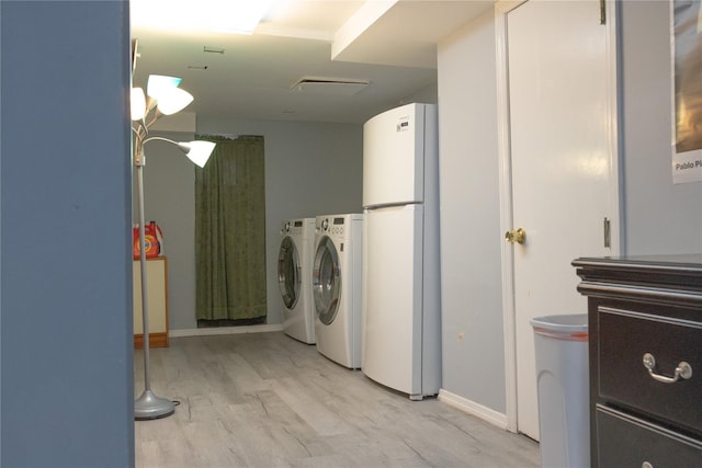 laundry area with washing machine and dryer and light hardwood / wood-style flooring