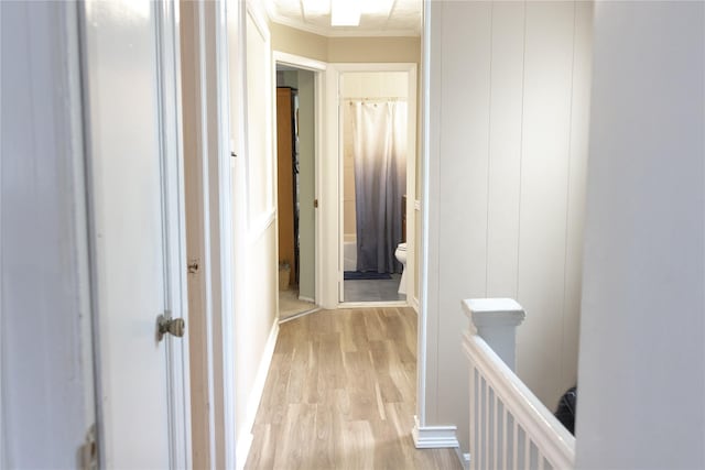 corridor featuring light wood-type flooring and ornamental molding