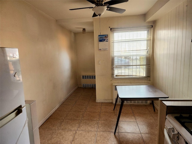 tiled dining room featuring ceiling fan and radiator