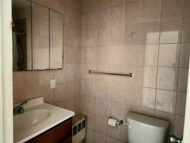 bathroom featuring radiator heating unit, toilet, vanity, and tile walls