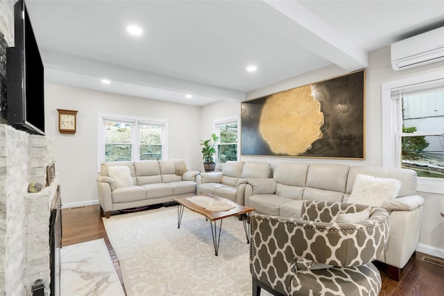 living room with a wall mounted AC, beam ceiling, a fireplace, and wood-type flooring