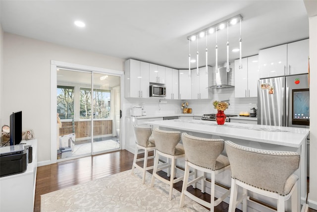 kitchen featuring white cabinets, decorative backsplash, wall chimney range hood, and stainless steel appliances