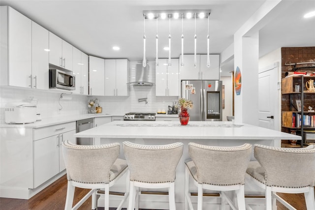 kitchen featuring a center island, stainless steel appliances, white cabinetry, and wall chimney exhaust hood