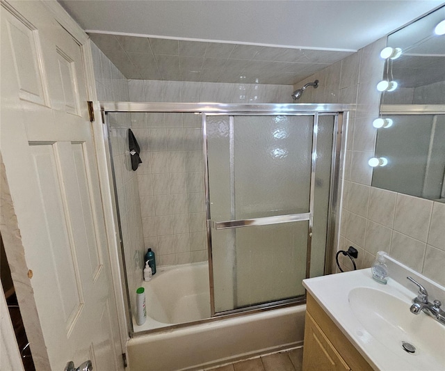 bathroom featuring enclosed tub / shower combo, tile walls, and vanity