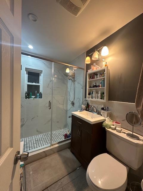 bathroom featuring walk in shower, vanity, tile patterned floors, and toilet