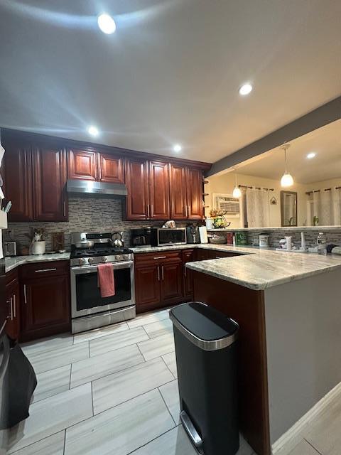 kitchen with an AC wall unit, pendant lighting, stainless steel appliances, tasteful backsplash, and kitchen peninsula