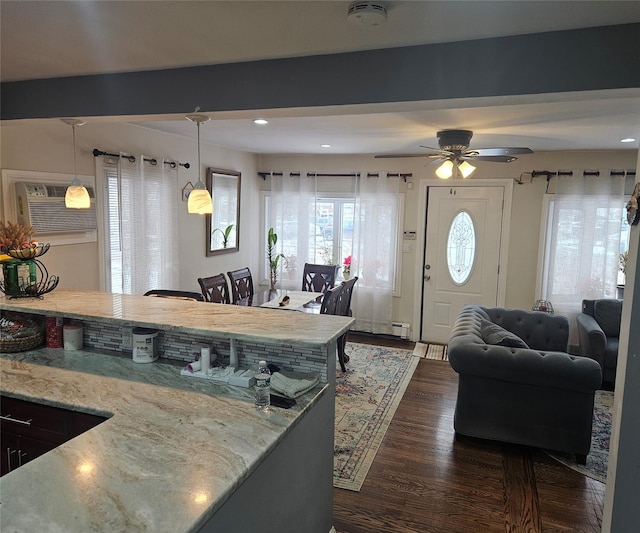 kitchen with hanging light fixtures, a wall mounted AC, dark hardwood / wood-style flooring, and light stone countertops