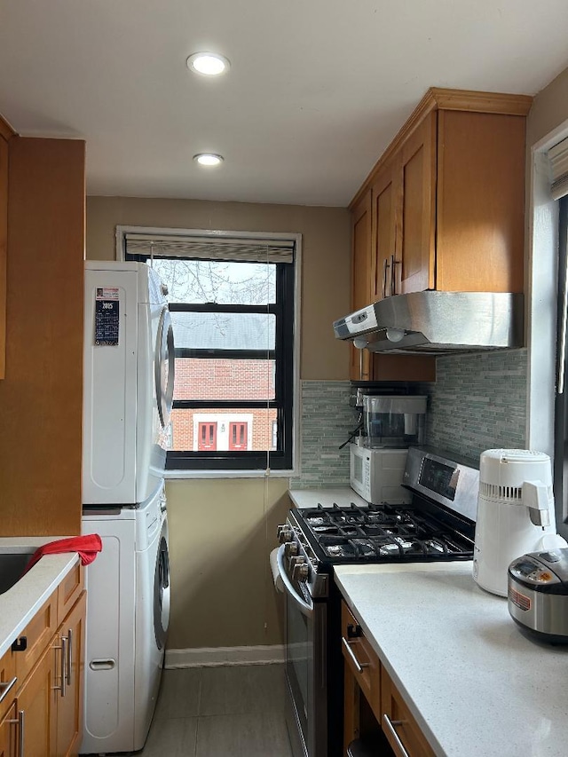 kitchen with stacked washing maching and dryer, decorative backsplash, tile patterned floors, and stainless steel range with gas stovetop