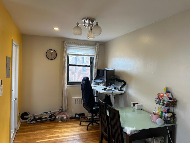 office featuring light wood-type flooring, radiator, and electric panel