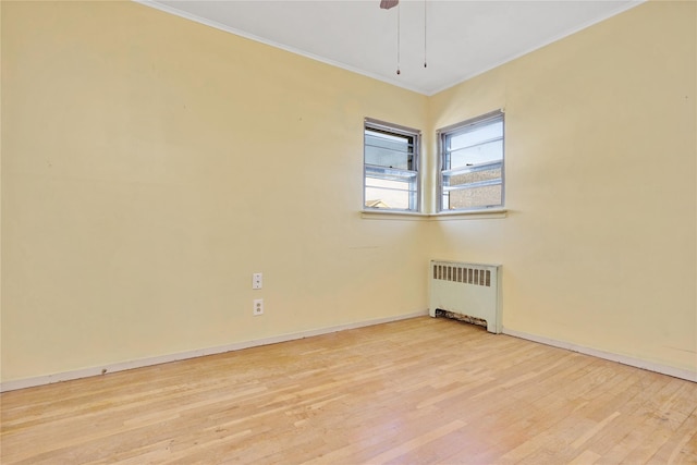 empty room featuring radiator, crown molding, and light hardwood / wood-style floors