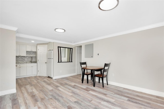 dining area featuring sink, light hardwood / wood-style flooring, and crown molding