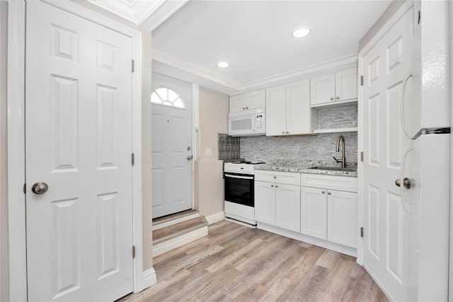 kitchen with light stone countertops, white appliances, white cabinetry, decorative backsplash, and sink