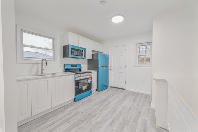 kitchen with refrigerator, sink, light hardwood / wood-style flooring, stainless steel range with electric stovetop, and white cabinets