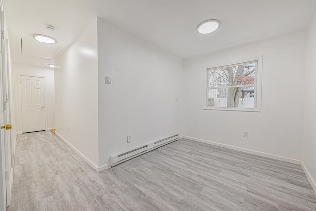 spare room featuring a baseboard heating unit and light hardwood / wood-style flooring