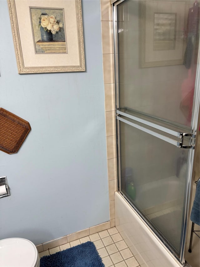 bathroom featuring toilet, enclosed tub / shower combo, and tile patterned floors