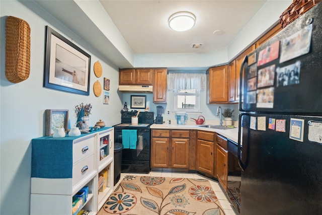 kitchen with light tile patterned floors, brown cabinetry, light countertops, black appliances, and a sink