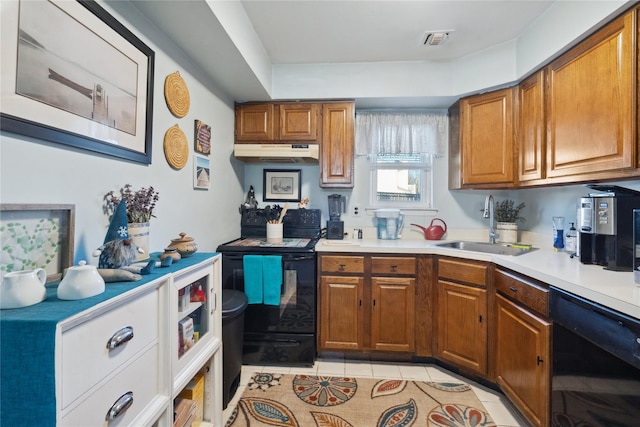 kitchen featuring brown cabinets, light countertops, under cabinet range hood, and black appliances