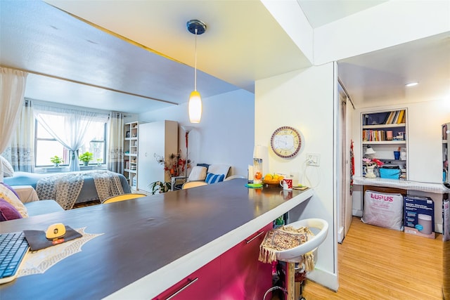 kitchen featuring built in shelves, light hardwood / wood-style flooring, and decorative light fixtures