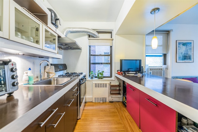 kitchen with range with gas cooktop, light hardwood / wood-style floors, hanging light fixtures, radiator, and sink