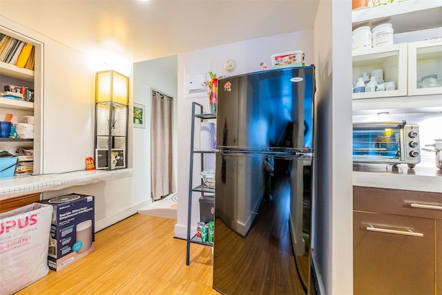 kitchen with black refrigerator, white cabinetry, and light hardwood / wood-style flooring