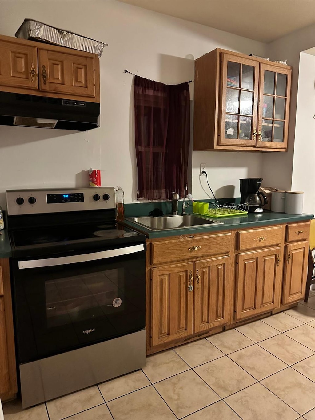 kitchen featuring electric range, sink, and light tile patterned flooring