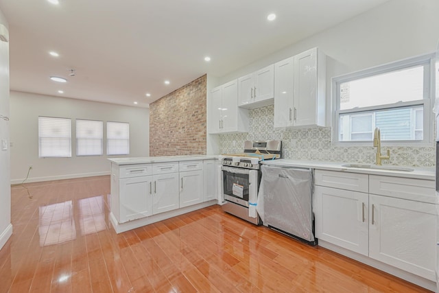 kitchen with appliances with stainless steel finishes, white cabinetry, sink, backsplash, and kitchen peninsula