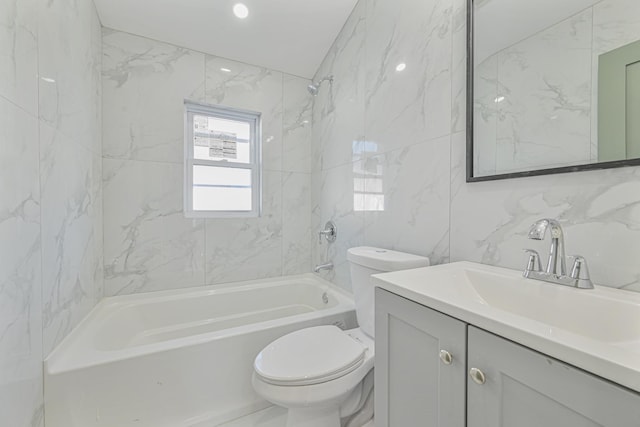 full bathroom featuring toilet, tiled shower / bath, tile walls, and vanity