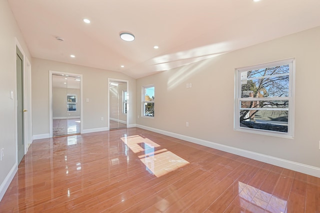 unfurnished room with vaulted ceiling, plenty of natural light, and wood-type flooring