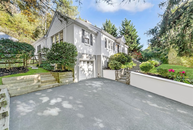 view of home's exterior with aphalt driveway, stairway, an attached garage, and stucco siding