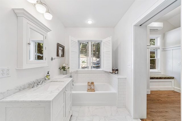 full bathroom with an AC wall unit, a garden tub, and vanity