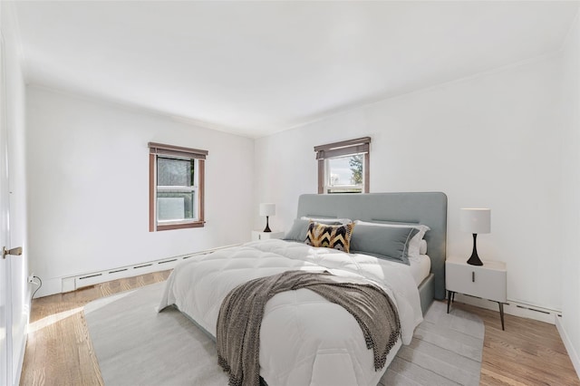 bedroom with light wood-style flooring and a baseboard heating unit