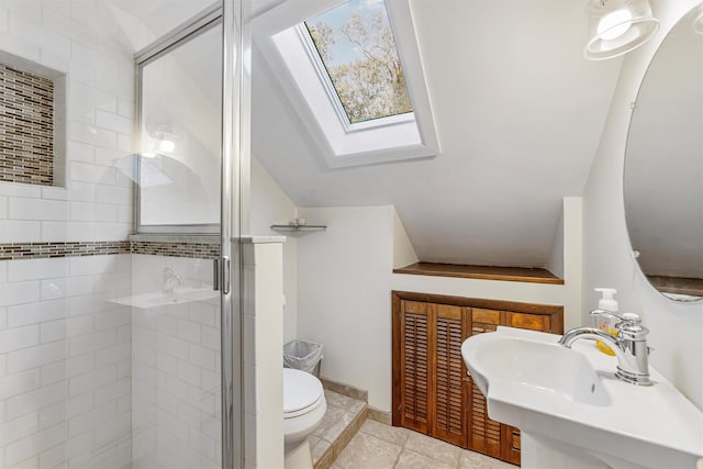 bathroom featuring a skylight, toilet, a stall shower, a sink, and tile patterned flooring