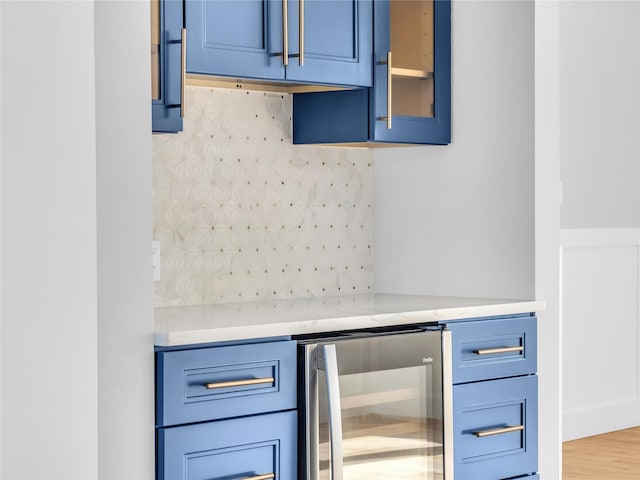 kitchen featuring blue cabinetry, light stone countertops, tasteful backsplash, hardwood / wood-style floors, and wine cooler