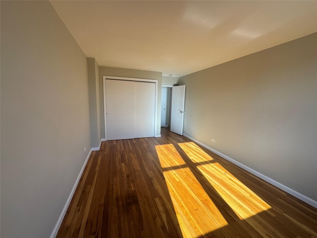 unfurnished bedroom with a closet and dark hardwood / wood-style flooring