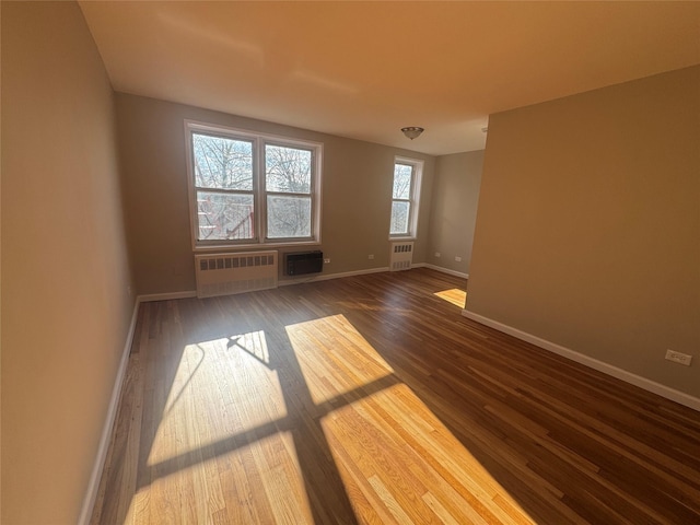 unfurnished room featuring dark hardwood / wood-style floors, radiator, and a wall mounted AC